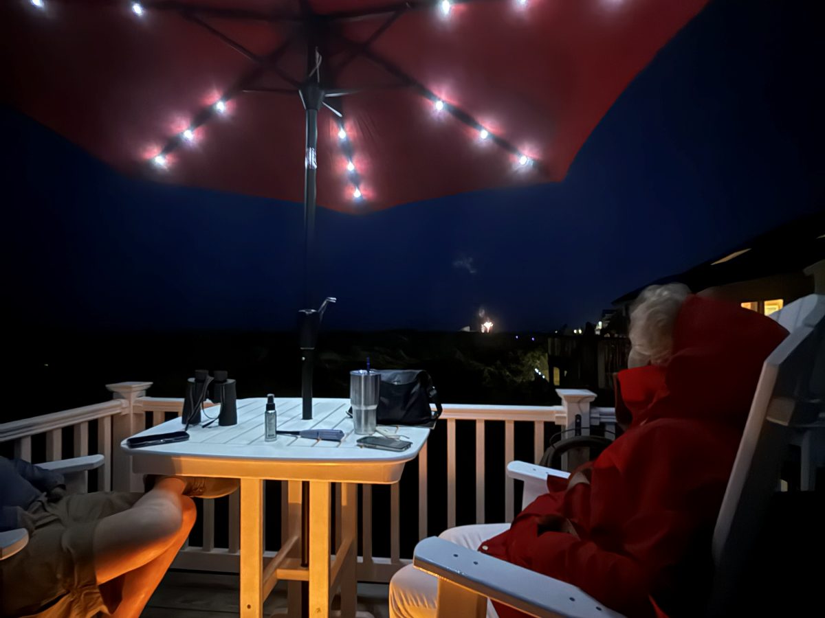 The deck at dusk under a red umbrella strung with lights