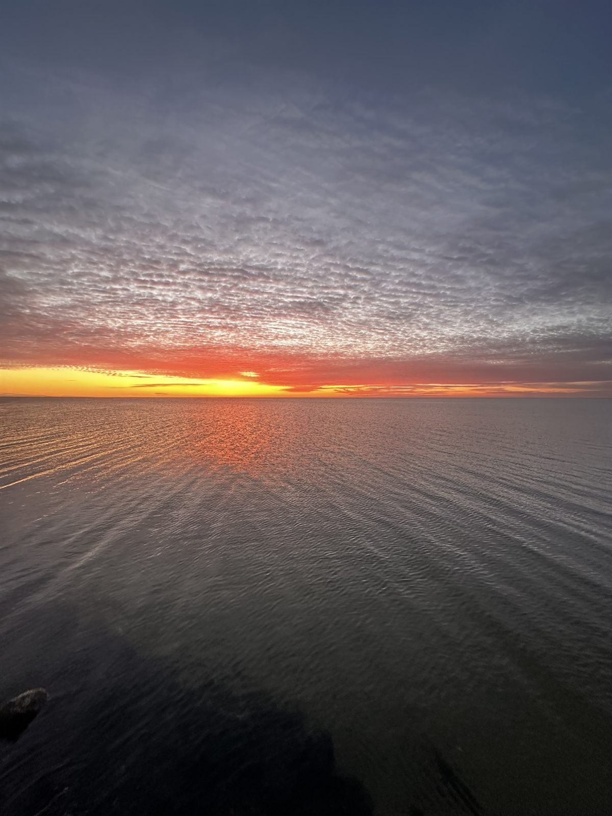 A fiery sunset reflected on calm water